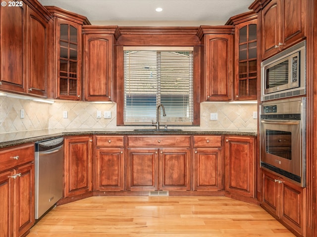1303 NE 147th Ave, Vancouver, WA 98684 - kitchen featuring stainless steel appliances, a sink, dark stone countertops, glass insert cabinets, and recessed lighting