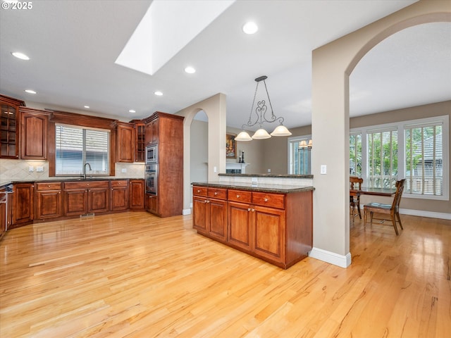 1303 NE 147th Ave, Vancouver, WA 98684 - kitchen featuring arched walkways, stainless steel appliances, light wood-type flooring, glass insert cabinets, and a sink
