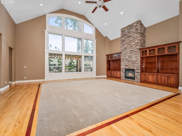 1303 NE 147th Ave, Vancouver, WA 98684 - unfurnished living room with high vaulted ceiling, light wood-style flooring, a ceiling fan, a stone fireplace, and baseboards