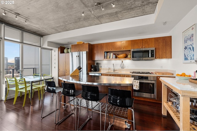 1926 W Burnside St Unit 1401, Portland, OR 97209 - kitchen with appliances with stainless steel finishes, brown cabinets, a sink, and dark wood finished floors