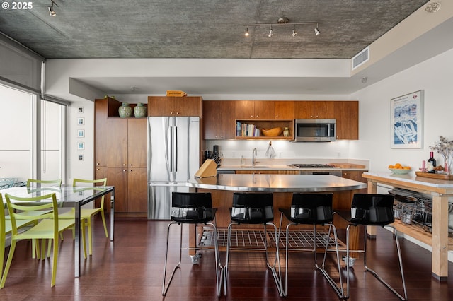 1926 W Burnside St Unit 1401, Portland, OR 97209 - kitchen with stainless steel appliances, brown cabinets, a sink, and dark wood finished floors