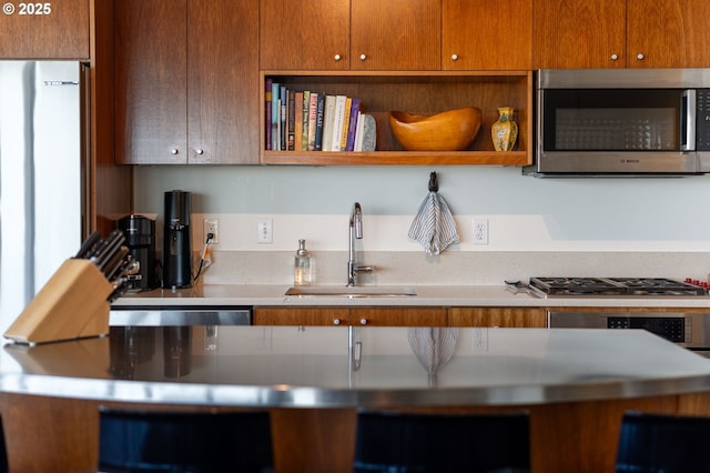 1926 W Burnside St Unit 1401, Portland, OR 97209 - kitchen featuring appliances with stainless steel finishes, a sink, light countertops, brown cabinetry, and open shelves