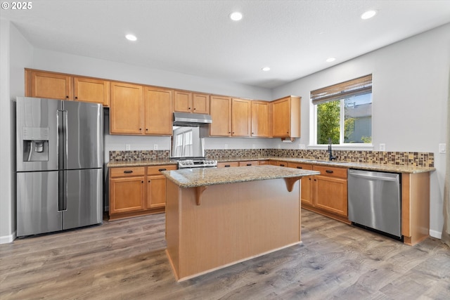 12800 Joys Dr, Oregon City, OR 97045 - kitchen with appliances with stainless steel finishes, a sink, under cabinet range hood, light stone countertops, and a center island