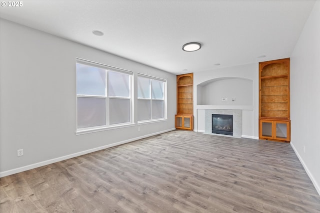 12800 Joys Dr, Oregon City, OR 97045 - unfurnished living room with built in shelves, baseboards, a tiled fireplace, and wood finished floors