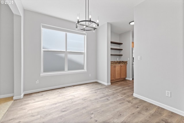 12800 Joys Dr, Oregon City, OR 97045 - unfurnished dining area with a chandelier, light wood-style flooring, and baseboards