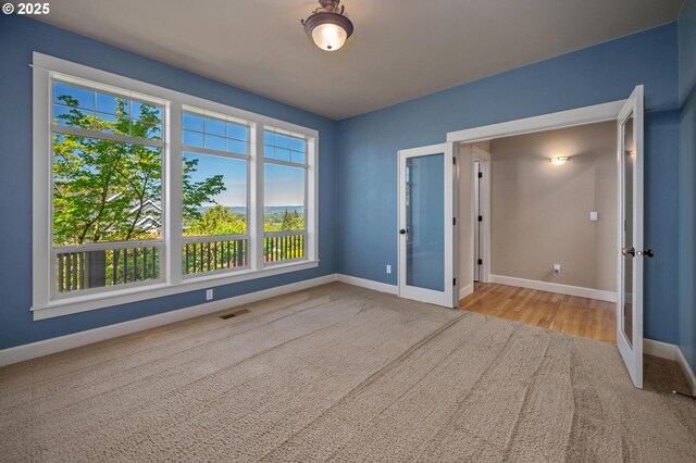 empty room featuring french doors, baseboards, and carpet