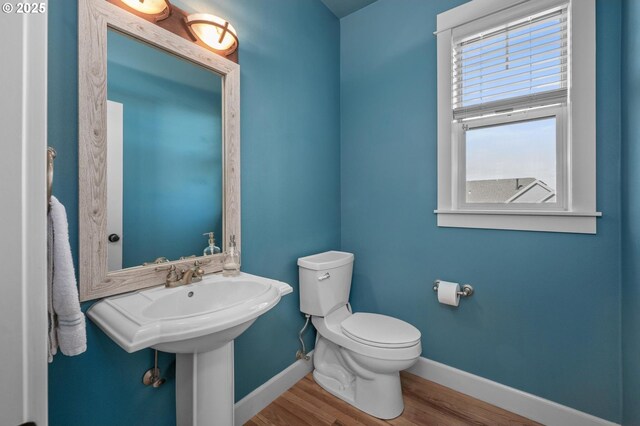 bathroom featuring baseboards, wood finished floors, and toilet