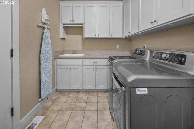 laundry area featuring washing machine and dryer, cabinet space, baseboards, and light tile patterned floors