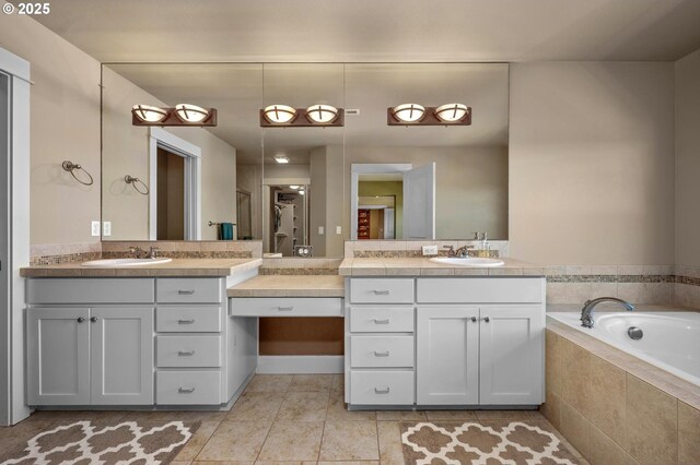 bathroom featuring two vanities, tile patterned flooring, and tiled bath