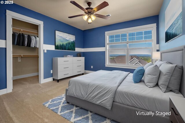 bedroom featuring carpet floors, baseboards, a walk in closet, a closet, and ceiling fan