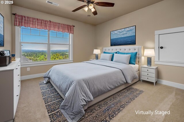 bedroom featuring light colored carpet, baseboards, and ceiling fan