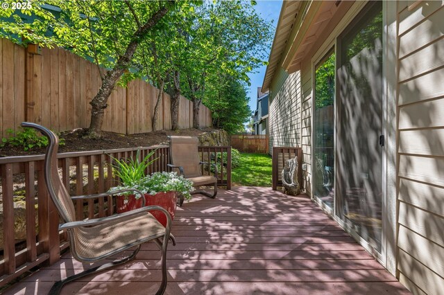 wooden terrace with a fenced backyard