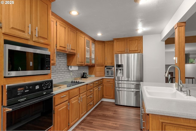 kitchen featuring sink, backsplash, dark hardwood / wood-style flooring, and black appliances