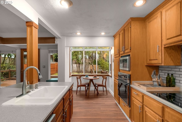 kitchen featuring black appliances, dark wood-type flooring, sink, decorative columns, and tasteful backsplash