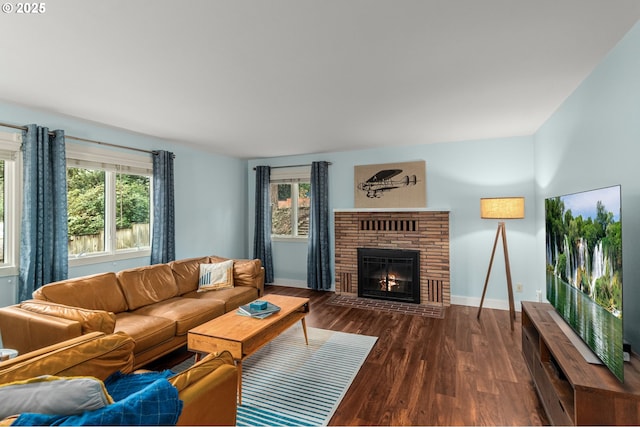 living room featuring a healthy amount of sunlight, a brick fireplace, and dark hardwood / wood-style floors