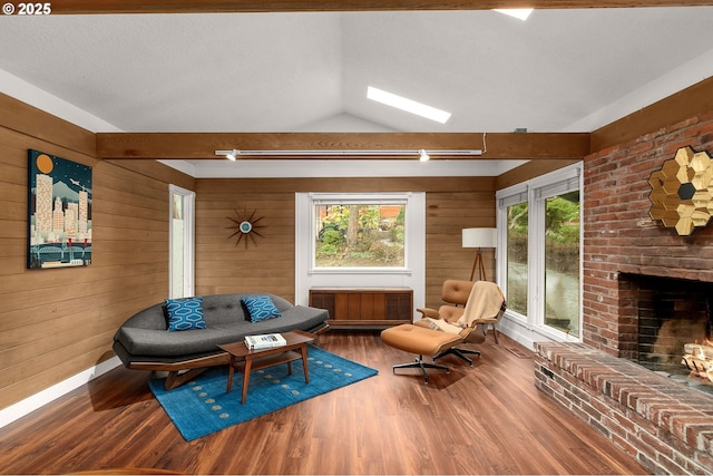 sitting room with vaulted ceiling, a brick fireplace, wooden walls, and hardwood / wood-style floors