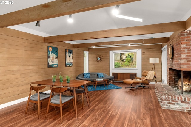 dining area featuring wood walls, hardwood / wood-style flooring, and a fireplace