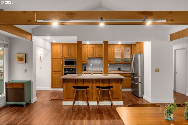 kitchen with an island with sink, a kitchen bar, backsplash, appliances with stainless steel finishes, and sink