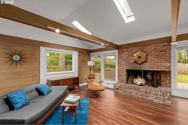 living room featuring a brick fireplace, radiator heating unit, plenty of natural light, and vaulted ceiling with skylight