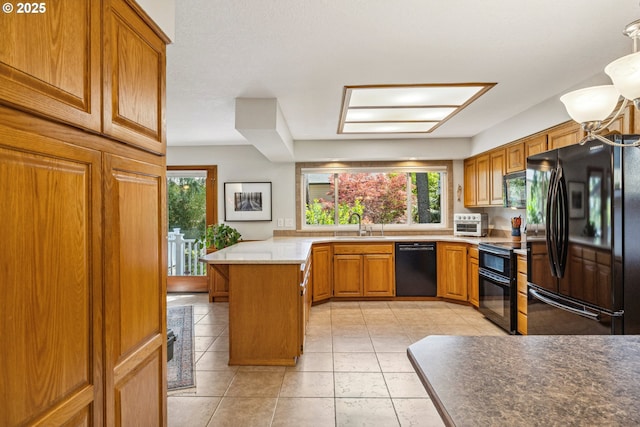 kitchen with brown cabinetry, a peninsula, light countertops, a sink, and black appliances