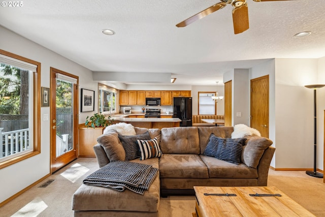 living room featuring baseboards, visible vents, light carpet, and ceiling fan with notable chandelier