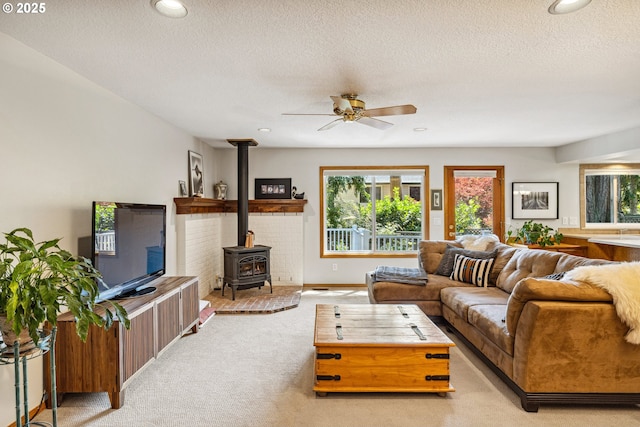 carpeted living room featuring recessed lighting, a wood stove, a textured ceiling, and ceiling fan