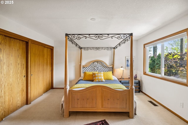 bedroom with visible vents, a textured ceiling, baseboards, and light carpet