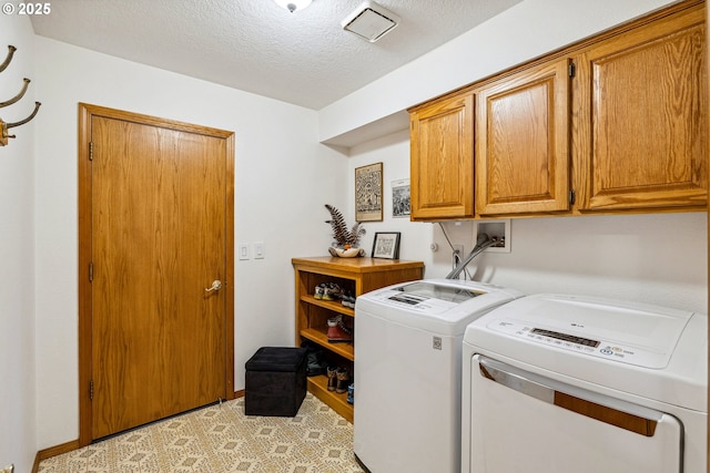 washroom with baseboards, a textured ceiling, cabinet space, and washer and clothes dryer