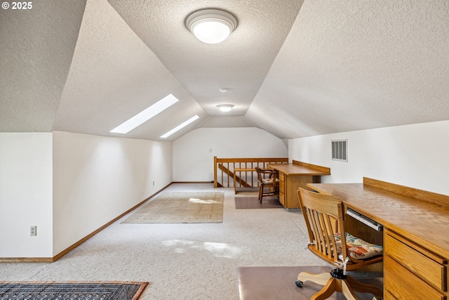 office area with vaulted ceiling with skylight, carpet, a textured ceiling, and visible vents