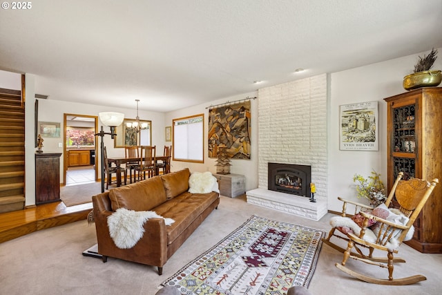 living area with stairs, a notable chandelier, light colored carpet, and a brick fireplace