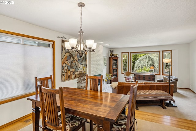 dining room featuring baseboards, visible vents, a textured ceiling, and a notable chandelier