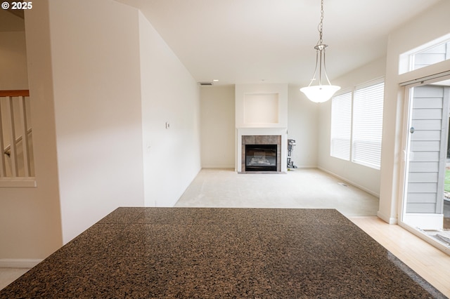 unfurnished living room with baseboards, light wood-style flooring, visible vents, and a tiled fireplace
