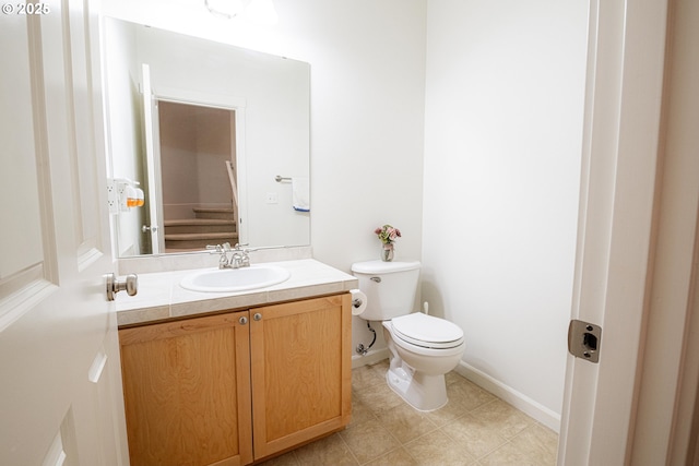 bathroom with baseboards, toilet, vanity, and tile patterned floors