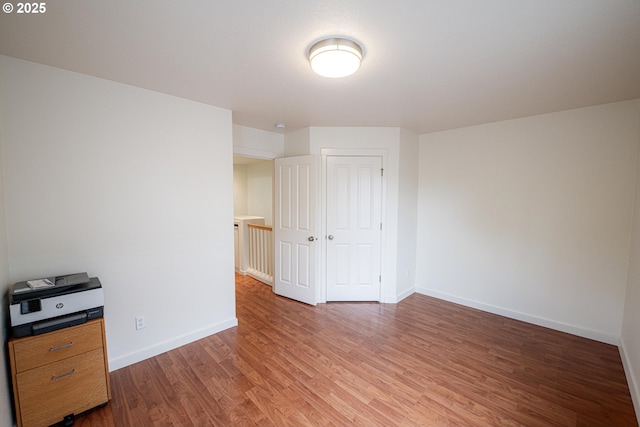 unfurnished bedroom with a closet, light wood finished floors, and baseboards