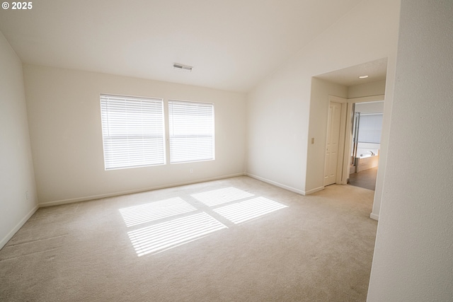 carpeted spare room with baseboards, vaulted ceiling, and visible vents
