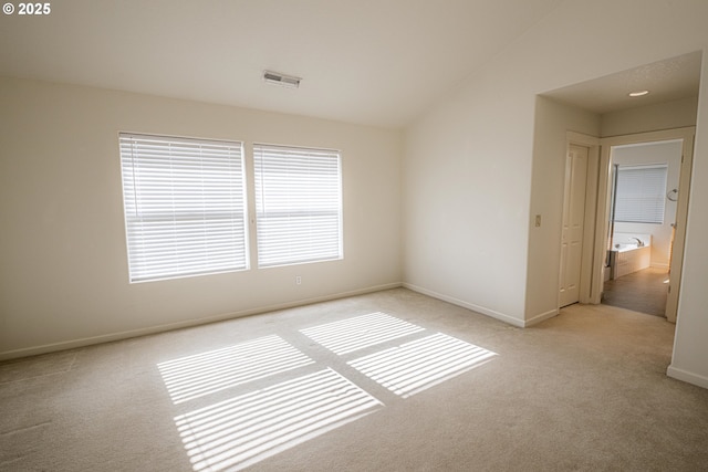 spare room featuring visible vents, baseboards, and light carpet