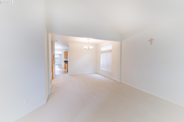 spare room with baseboards, a notable chandelier, and light colored carpet