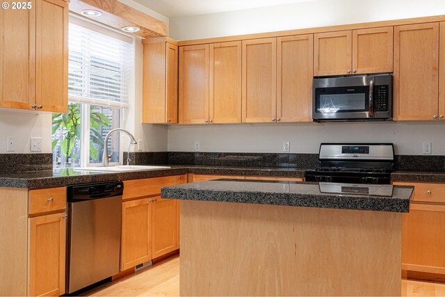 kitchen with a kitchen island, appliances with stainless steel finishes, light brown cabinets, and a sink