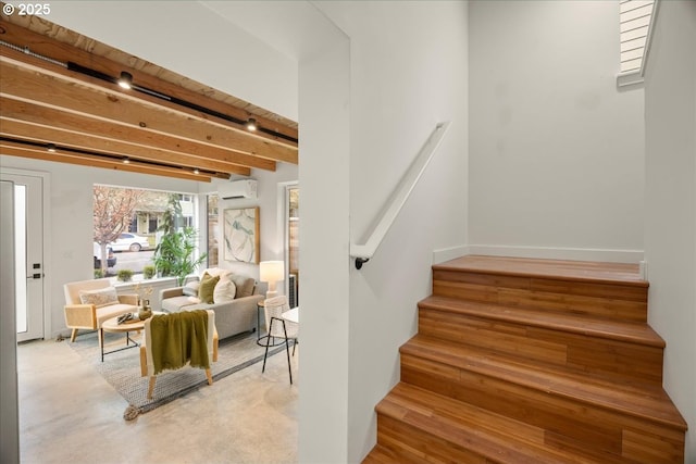 staircase with a wall unit AC, wood finished floors, and beam ceiling