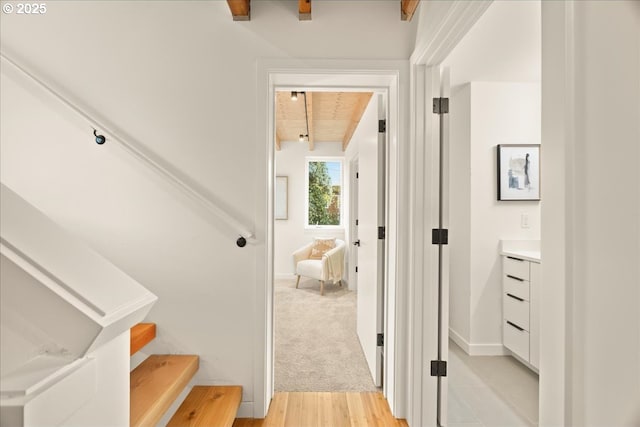 stairway featuring beamed ceiling, wood finished floors, and baseboards