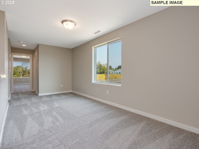 empty room with visible vents, baseboards, and light colored carpet