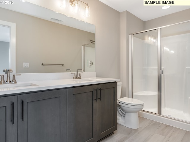 bathroom featuring a stall shower, toilet, visible vents, and a sink