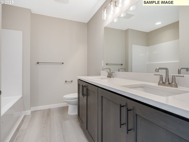 full bathroom with toilet, wood finished floors, baseboards, and a sink