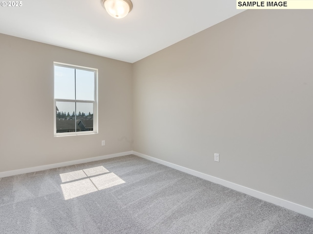 carpeted empty room featuring baseboards