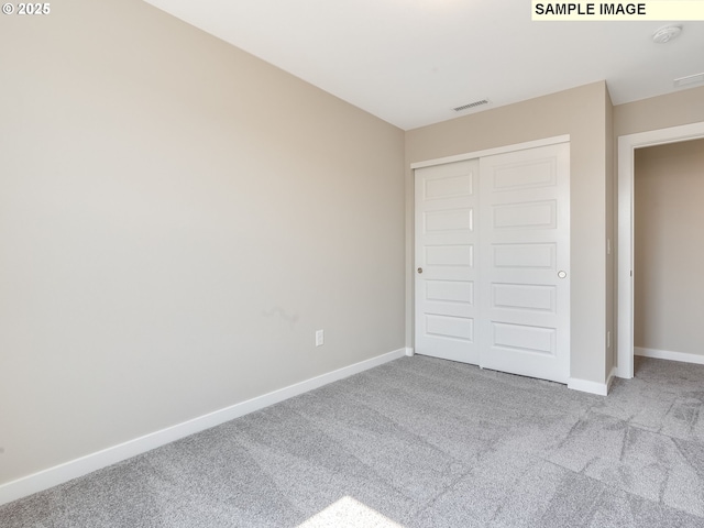 unfurnished bedroom with visible vents, baseboards, carpet, and a closet