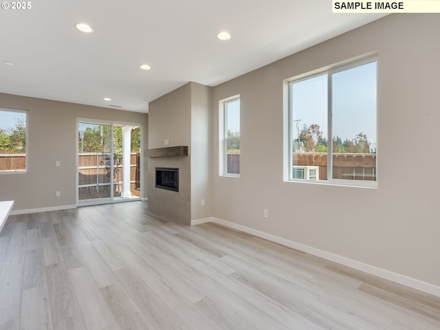 unfurnished living room featuring recessed lighting, baseboards, light wood-style flooring, and a tile fireplace