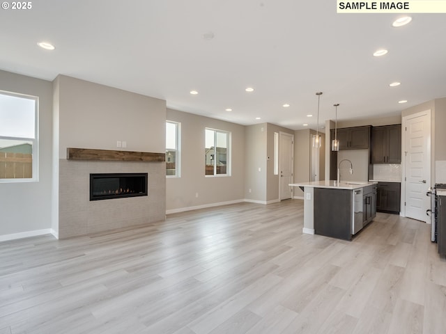 kitchen featuring light countertops, light wood-style flooring, open floor plan, and a sink