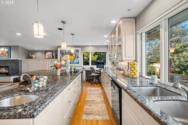 kitchen featuring dishwasher, white cabinetry, sink, hanging light fixtures, and light hardwood / wood-style flooring