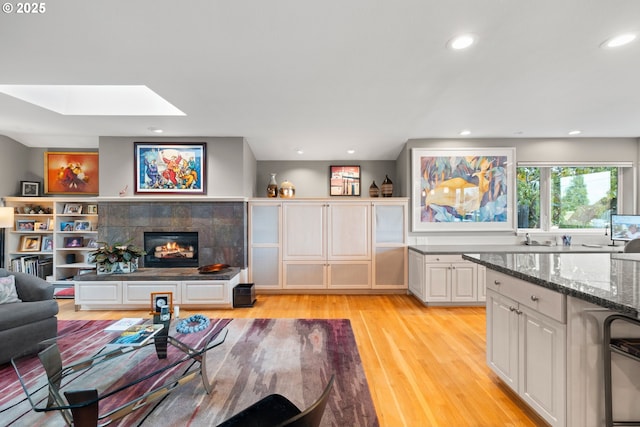 living room with a fireplace, a skylight, and light hardwood / wood-style floors