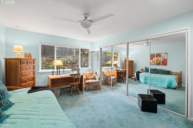 bedroom featuring ceiling fan, carpet flooring, a closet, and a textured ceiling